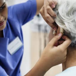 Older woman being fitted for a hearing aid.