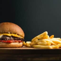 Cheeseburger and fries in front of a black background.