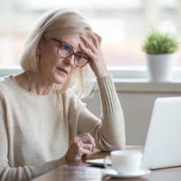 Senior woman feeling frustrated and confused as she looks at her laptop.