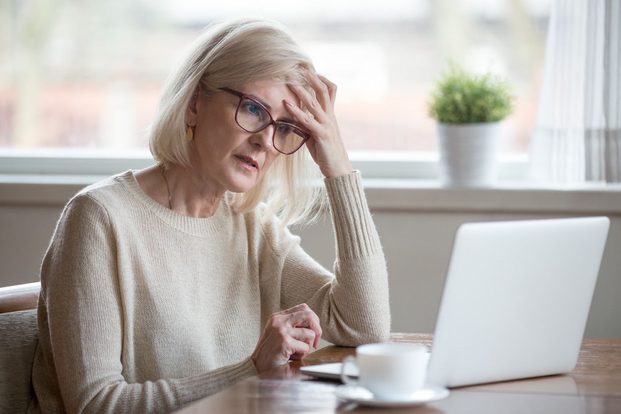 Senior woman feeling frustrated and confused as she looks at her laptop.