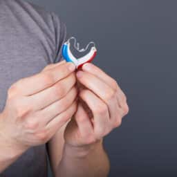 Man holds two hearing aids