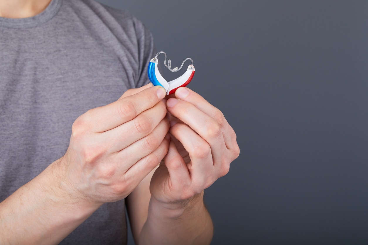 Man holds two hearing aids